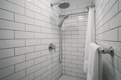 Mitigeur de douche chromé installé à hauteur optimale dans une petite salle de bains carrelée en blanc